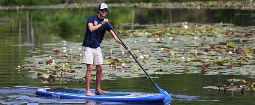 Student paddle boarding on water on campus.
